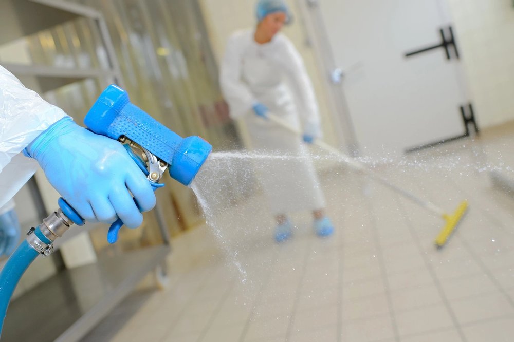 Person spraying sanitizer on a tiled floor